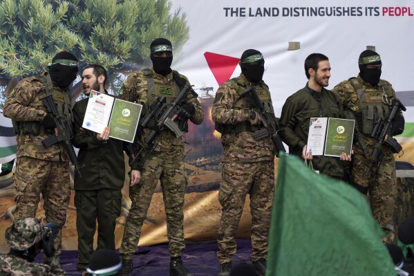 Israeli hostages Eliya Cohen, left, and Omer Shem Tov are escorted by Hamas fighters before being handed over to the Red Cross in Nuseirat, central Gaza Strip, Saturday, Feb. 22, 2025. (AP Photo/Abdel Kareem Hana)