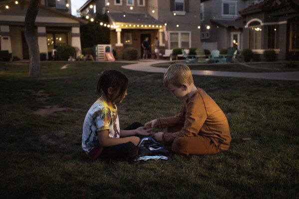 Maverick, left, and Brennan, right, play in Agritopia's "kid pod," a cluster of families with more than 20 kids between them at Agritopia, a community nestled around a plot of agricultural land, on April 21, 2025, in Gilbert, Ariz. (AP Photo/Annika Hammerschlag)