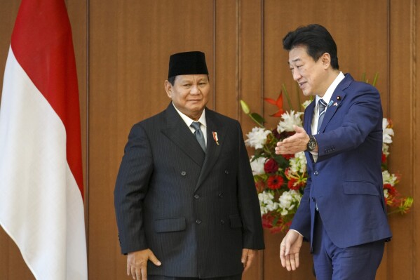 Indonesian Defense Minister and President-elect Prabowo Subianto, left, is shown the seat for talks by Japanese counterpart Minoru Kihara, right, at the Defense Ministry in Tokyo, Japan, Wednesday, April 3, 2024. (Kimimasa Mayama/Pool Photo via AP)