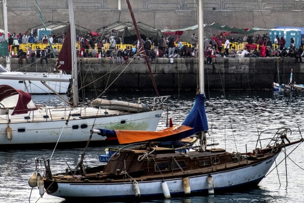 FILE - Migrants stand at the Arguineguin port in Gran Canaria island, Spain, after being rescued in the Atlantic Ocean by emergency workers on Thursday, Oct. 12, 2020. The deployment of two Spanish surveillance planes to watch for migrant boats heading on the treacherous route from West Africa to Spain’s Canary Islands has enabled authorities to stop 59 canoes from Senegal and Gambia carrying around 7,200 migrants in the past two months, a senior Spanish official said Friday, Dec. 15, 2023. (AP Photo/Javier Bauluz, File)