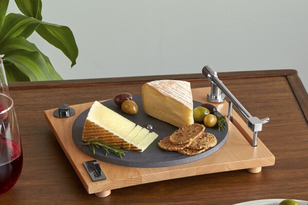 This image released by Uncommon Goods shows a cheese board designed to look like the most expensive, slick turntable, featuring a slate platter and hidden slicer in the one arm. (Uncommon Goods via AP)