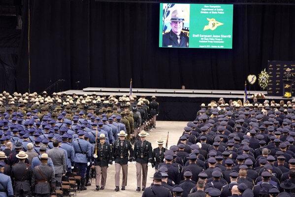 FILE - A likeness of New Hampshire State Police Staff Sgt. Jesse Sherrill appears on a screen, top, during a Celebration of Life service for Sherrill at the SNHU Arena, Nov. 3, 2021, in Manchester, N.H. Jay Medeiros, a Connecticut truck driver will serve at least 12 months behind bars after pleading guilty to charges Friday, Jan 12, 2024, related to a highway crash that killed the New Hampshire state trooper. (AP Photo/Steven Senne, file)