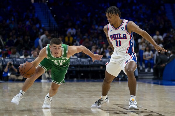 Boston Celtics' Payton Pritchard, left, drives against Philadelphia 76ers' Jaden Springer during the first half of a preseason NBA basketball game Wednesday, Oct. 11, 2023, in Philadelphia. (AP Photo/Chris Szagola)