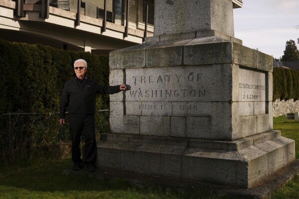 Brian Calder, a fourth-generation resident and dual citizen, poses for a portrait at a historic international boundary marker between the United Sates and Canada, Tuesday, March 18, 2025, in Point Roberts, Wash. (AP Photo/Lindsey Wasson)