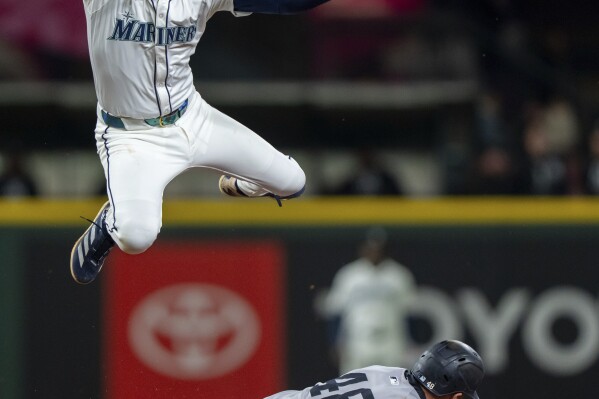 New York Yankees' Paul Goldschmidt steals second base below the tag of Seattle Mariners shortstop J.P. Crawford during the ninth inning of a baseball game, Tuesday, May 13, 2025, in Seattle. (AP Photo/Stephen Brashear)