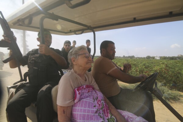 Palestinians transport a captured Israeli civilian, center, from Kibbutz Kfar Azza into the Gaza Strip on Saturday, Oct. 7, 2023. (AP Photo/Hatem Ali)