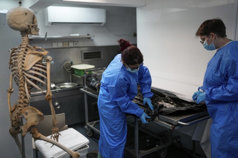 Israeli forensic experts work on bodies of Israelis killed by Hamas militants in the National Center for Forensic Medicine in Tel Aviv, Israel, Wednesday, Oct. 18, 2023. (AP Photo/Ohad Zwigenberg)