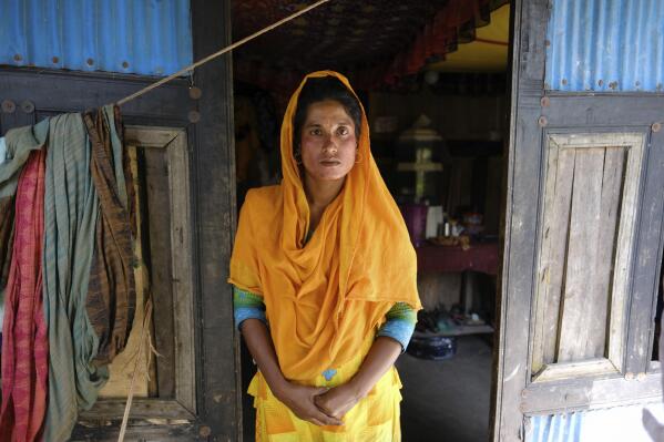 Monira Khatun, 29, stands by the door of her house in Chila Bazar, in Mongla, Bangladesh, March 4, 2022. Her father died soon as she returned back home, after being abandoned by her husband, leaving her to shoulder three other family members' care. “My parents’ home was gone to the river for erosion, we had no land to cultivate,” Khatun said. She ended up working at a factory in a special economic zone that employs thousands of climate refugees in the southwestern town of Mongla, where Bangladesh’s second-largest seaport is located. (AP Photo/Mahmud Hossain Opu)
