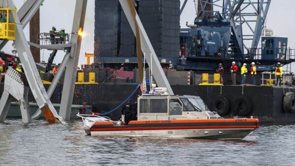 In this photo provided by the U.S. Coast Guard, a Coast Guard Station Crisfield 29-foot response boat-small crew observes as demolition crews cut the top portion of the north side of the collapsed Francis Scott Key Bridge into smaller sections for safe removal by crane in the Patapsco River, in Baltimore, Saturday, March 30, 2024. Salvage teams used an exothermic cutting torch to systematically separate sections of the steel bridge, which will be taken to a disposal site. (Petty Officer 3rd Class Kimberly Reaves/U.S. Coast Guard via AP)
