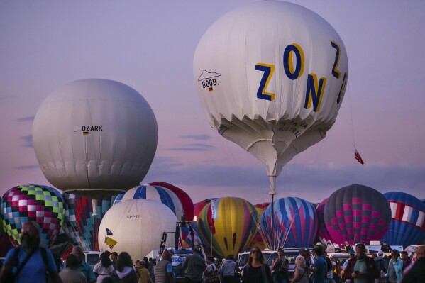 The Poland-1 gas balloon, center right, slowly inflates in preparation for the launch of the 66th Coupe Aéronautique Gordon Bennett gas balloon race at Balloon Fiesta Park in Albuquerque, N.M., on Saturday, Oct. 7, 2023. A fiery crash during the prestigious long-distance ballooning race has left two pilots from Poland, Krzystotf Zapart and Pjotr Halas, with burns and other injuries. Authorities say the team’s hydrogen-filled balloon struck a high-voltage power line at an electrical substation in North Texas on Monday. (Chancey Bush/The Albuquerque Journal via AP)