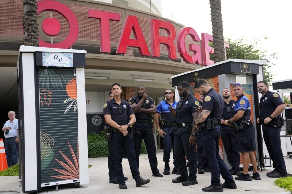 FILE - Police officers stand outside of a Target store as a group of people across the street protest against Pride displays in the store on June 1, 2023, in Miami. Target confirmed that it won't be carrying its LGBTQ+ merchandise for Pride month in June, 2024, in some stores after the discount retailer received backlash last year for its assortment. (AP Photo/Lynne Sladky, File)