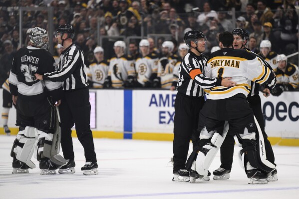 Boston Bruins goaltender Jeremy Swayman, right, is held back from fighting Los Angeles Kings goaltender Darcy Kuemper during the second period of an NHL hockey game Sunday, March 23, 2025, in Los Angeles. (AP Photo/William Liang)