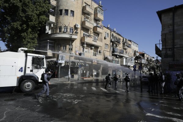 Israeli police shoot a water canon towards protesters in an ultra-orthodox neighborhood of Jerusalem, Sunday, Jan. 24, 2021. Ultra-Orthodox demonstrators clashed with Israeli police officers dispatched to close schools in Jerusalem and Ashdod that had opened in violation of health regulations on Sunday. (AP Photo/Sebastian Scheiner)