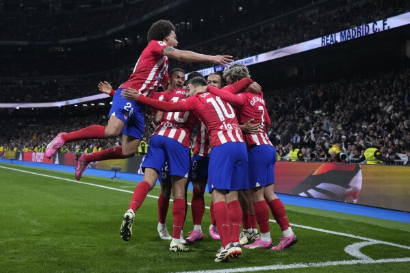 Atletico Madrid's team players celebrate after Marcos Llorente scored their side's first goal during the Spanish La Liga soccer match between Real Madrid and Atletico Madrid at the Santiago Bernabeu stadium in Madrid, Spain, Sunday, Feb. 4, 2024. (AP Photo/Bernat Armangue)