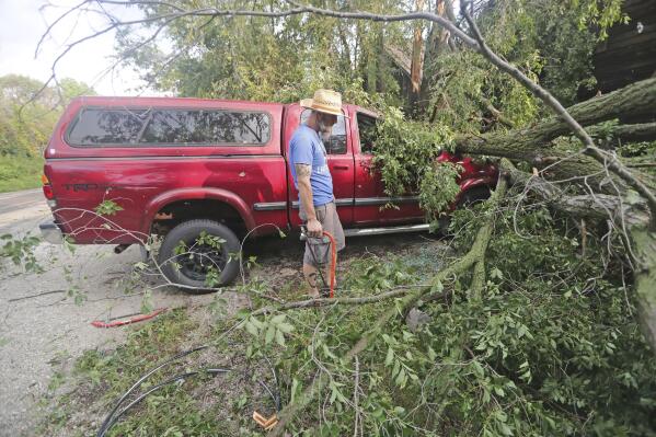 Adam Turley surveys the damage to his dad's truck in front of their home on Concord Center Drive in the Town of Concord, Wis., on Thursday, July 29, 2021. A line of thunderstorms arrived early Thursday generating numerous tornado warnings as well as high winds and near-constant lightning.  (Mike De Sisti/Milwaukee Journal-Sentinel via AP)