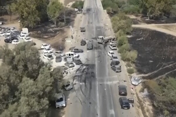 This image from video provided by South First Responders shows charred and damaged cars along a desert road after an attack by Hamas militants at the Tribe of Nova Trance music festival near Kibbutz Re'im in southern Israel on Saturday, Oct. 7, 2023. (South First Responders via AP)