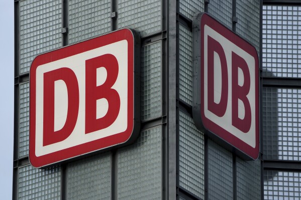 FILE - Two logos of the 'Deutsche Bahn' (German Railroad) are pictured at the main train station in Berlin, Germany, Monday, Jan. 3, 2022. Germany's main national railway operator, Deutsche Bahn, on Tuesday launched an effort to sell its logistics unit, DB Schenker, as the company seeks to concentrate on its core business at home. (AP Photo/Michael Sohn, File)
