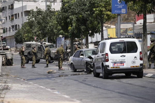 Israeli soldiers work at the site of an alleged car-ramming attack near Beit Hagai, a Jewish settlement in the hills south of the large Palestinian city of Hebron, Wednesday, Aug. 30, 2023. The Israeli military said security forces shot the Palestinian driver as he accelerated toward a military post. A soldier struck by the car was evacuated to a nearby hospital for treatment. There was no immediate word on the condition of the suspected Palestinian assailant. (AP Photo/Mahmoud Illean)
