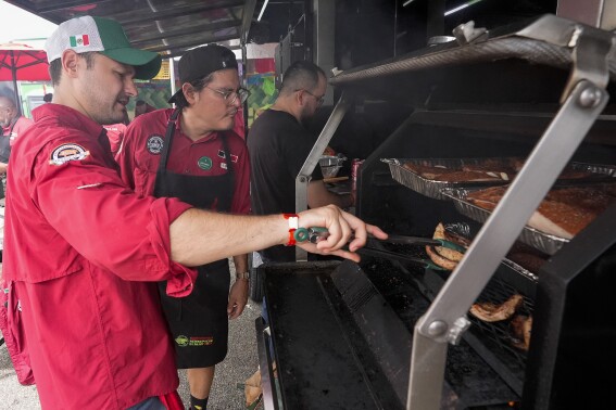Marcelo Trevino, left, and Arturo Gutierrez of the Sociedad Mexicano de Parrillieros team check food on the grill at the World Championship Barbecue Cooking Contest, Friday, May 17, 2024, in Memphis, Tenn. (AP Photo/George Walker IV)