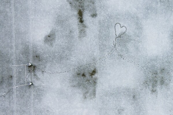 Footprints create the shape of a heart in a snow-covered rugby field in Santiago, Chile, Wednesday, May 8, 2024. (AP Photo/Matias Basualdo)