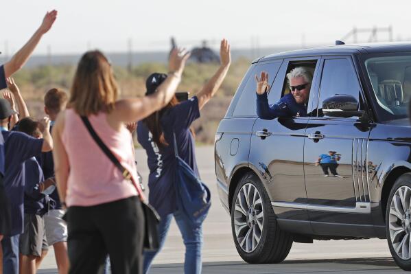 Virgin Galactic founder Richard Branson waves to school children while heading to board the rocket plane that will fly him to space from Spaceport America near Truth or Consequences, New Mexico, Sunday, July 11, 2021. (AP Photo/Andres Leighton)