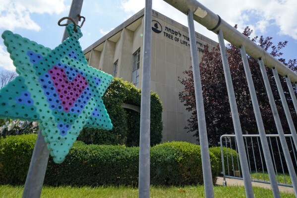 A Star of David hangs from a fence outside the dormant landmark Tree of Life synagogue in Pittsburgh's Squirrel Hill neighborhood on Thursday, July 13, 2023, the day a federal jury announced they had found Robert Bowers, who in 2018 killed 11 people at the synagogue, eligible for the death penalty. (AP Photo/Gene J. Puskar)