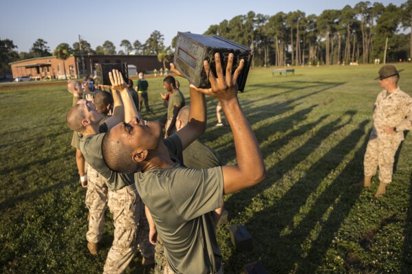 A group of male U.S. Marine Corps recruits train with weighted ammo cans during a physical training exercise at the Marine Corps Recruit Depot, Wednesday, June 28, 2023, in Parris Island, S.C. (AP Photo/Stephen B. Morton)