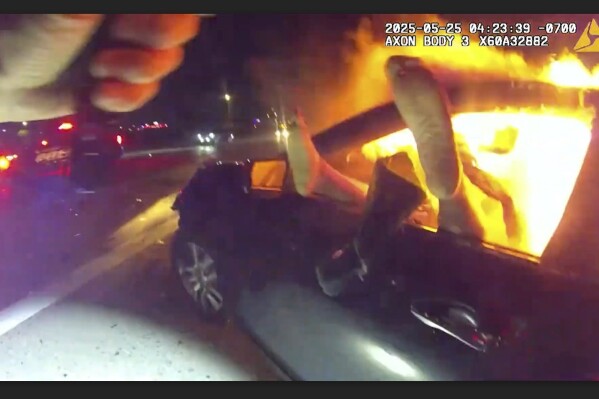 In this image taken from video released by the Goodyear Police Department, Officer Dakota Berry arrives at the scene of woman trapped inside a car fire on the interstate, May 24, 2025, in Phoenix, Ariz. (Goodyear Police Department via AP)