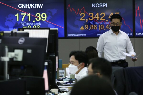 A currency trader walks with documents at the foreign exchange dealing room of the KEB Hana Bank headquarters in Seoul, South Korea, Wednesday, Sept. 23, 2020.Asian markets were mostly lower on Wednesday as investors kept a wary eye on how the coronavirus pandemic will affect the economic outlook.(AP Photo/Ahn Young-joon)