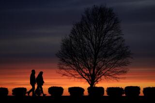FILE - In this Monday, April 13, 2020 file photo, a couple walks alone in a Kansas City, Mo., park at sunset as stay-at-home orders continue in much of the country in an effort to stem the spread of the new coronavirus. When most of the U.S. went into lockdown in 2020, some speculated that confining couples to their homes with little to entertain themselves would lead to a lot of baby-making. But the statistics suggest the opposite happened. (AP Photo/Charlie Riedel)