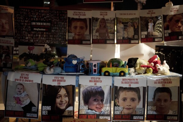 Posters of children held hostage by Hamas in the Gaza Strip are displayed with toys across from the Kirya, headquarters of Israel's Defense Forces ahead of an anticipated hostage release, in Tel Aviv, Israel, Thursday, Nov. 23, 2023. (AP Photo/Maya Alleruzzo)