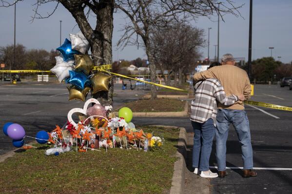 Debbie, left, and Chet Barnett place flowers at a memorial outside of the Chesapeake, Va., Walmart on Thursday, Nov. 24, 2022.  Andre Bing, a Walmart manager, opened fire on fellow employees in the break room of the Virginia store, killing six people in the country’s second high-profile mass shooting in four days, police and witnesses said Wednesday. (Billy Schuerman/The Virginian-Pilot via AP)