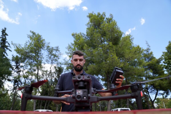 A drone pilot changes the batteries of a long-range drone equipped with thermal imaging cameras and a sophisticated early warning system, in the northern suburb of Nea Erithrea, Athens, Greece, Thursday, Aug. 10, 2023. Greece is plagued by hundreds of wildfires each summer. To protect their area from potentially deadly blazes, a group of residents from a suburb in northern Athens have joined forces to hire a company using long-range drones equipped with thermal imaging cameras and a sophisticated early warning system to catch fires before they can spread. (AP Photo/Thanassis Stavrakis)