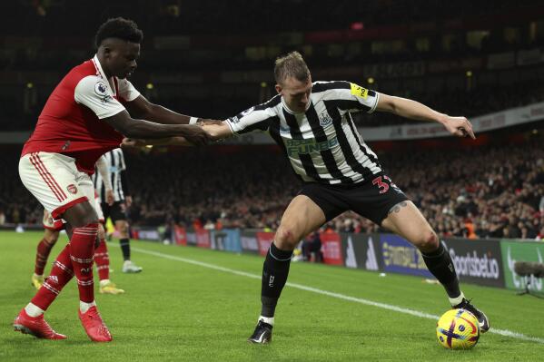 Arsenal's Bukayo Saka, left, duels for the ball with Newcastle's Dan Burn during the English Premier League soccer match between Arsenal and Newcastle United at Emirates stadium in London, Tuesday, Jan. 3, 2023. (AP Photo/Ian Walton)