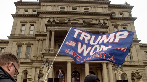 FILE - A protester waves a Trump flag during rally organized by a group called Election Integrity Fund and Force at the Michigan State Capitol, Tuesday, Oct. 12, 2021, in Lansing, Mich. Michigan Attorney General Dana Nessel has charged 16 Republicans Tuesday, July 18, 2023, with multiple felonies after they are alleged to have submitted false certificates stating they were the state’s presidential electors despite Joe Biden’s 154,000-vote victory in 2020. The group includes Republican National Committeewoman Kathy Berden and Meshawn Maddock, former co-chair of the Michigan Republican Party. (Jake May/The Flint Journal via AP, File)