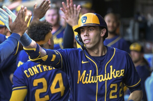 Milwaukee Brewers' Christian Yelich is congratulated in the dugout after hitting a two-run home run against the Minnesota Twins during the seventh inning of a baseball game Tuesday, June 13, 2023, in Minneapolis. (AP Photo/Craig Lassig)