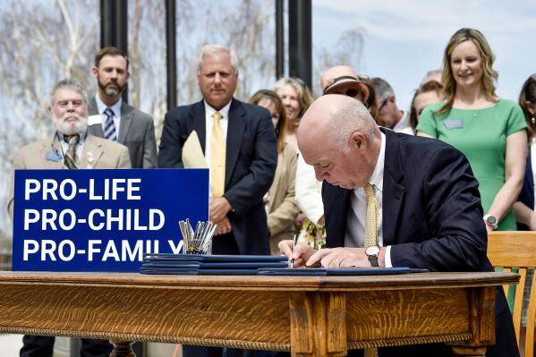 Gov. Greg Gianforte signs a suite of bills aimed at restricting access to abortion during a bill signing ceremony on the steps of the State Capitol, in Helena, Mont., on Wednesday, May 3, 2023. (Thom Bridge/Independent Record via AP)