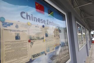 FILE - A display case of photos is seen outside the Chinese Embassy in Honiara, Solomon Islands on April 2, 2022. A Chinese state-owned company is negotiating to buy a forestry planation with a deep-water port and World War II airstrip in Solomon Islands, as concerns continue that China wants to establish a naval foothold in the South Pacific country. (AP Photo/Charley Piringi, File)