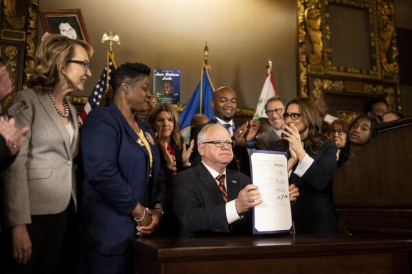 Minnesota Gov. Tim Walz holds up a just-signed gun control bill Friday, May 19, 2023, at the Minnesota State Capitol in St. Paul, Minn. Walz signed a sweeping public safety bill into law, including two gun measures: universal background checks and a red flag-style provision allowing law enforcement to intervene when someone is at high risk of injuring themselves or others with a firearm. (Aaron Lavinsky@startribune.com/Star Tribune via AP)