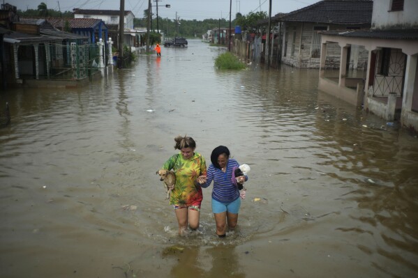 Residents wade through a street flooded by rains brought on by Hurricane Idalia, in Batabano, Cuba, Tuesday, Aug. 29, 2023. (AP Photo/Ramon Espinosa)