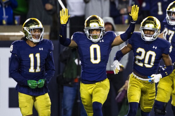 Notre Dame safety Xavier Watts (0) celebrates an interception along side safety Ramon Henderson (11) and cornerback Benjamin Morrison (20) during the first half an NCAA college football game against Southern California Saturday, Oct. 14, 2023, in South Bend, Ind. (AP Photo/Michael Caterina)