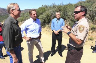 FILE - This photo taken Aug. 10, 2017, shows then-Yavapai County sheriff's Chief Deputy David Rhodes, right, speaking with then-Arizona U.S. Sen. Jeff Flake, center, during a tour of an area threatened by a wildfire. Rhodes, who is now the Yavapai County sheriff, pleaded guilty in federal court Thursday, Dec. 2, 2021, to operating a boat while under the influence of alcohol at Lake Powell. (AP Photo/Bob Christie, File)