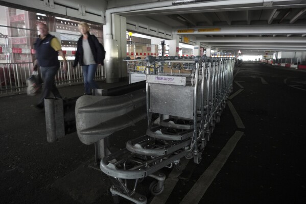 Travellers walk through the dark car park at Terminal 4 as Britain's Heathrow Airport has closed for the full day Friday after an electrical substation fire knocked out its power, disrupting flights for hundreds of thousands of passengers at one of Europe's biggest travel hubs in London, Friday, March 21, 2025.(AP Photo/Kin Cheung)