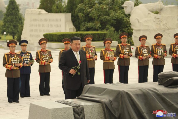 In this photo provided by the North Korean government, North Korean leader Kim Jong Un, foreground, prepares to offer a flower at a liberation war martyrs cemetery in Pyongyang, North Korea Tuesday, July 25, 2023, on the occasion of the 70th anniversary of the armistice that halted fighting in the 1950-53 Korean War. Independent journalists were not given access to cover the event depicted in this image distributed by the North Korean government. The content of this image is as provided and cannot be independently verified. Korean language watermark on image as provided by source reads: "KCNA" which is the abbreviation for Korean Central News Agency. (Korean Central News Agency/Korea News Service via AP)