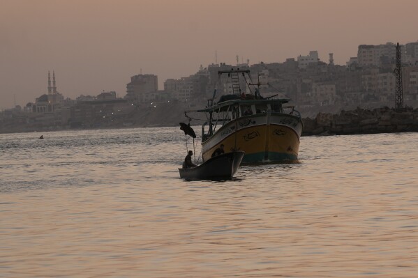 Palestinian fishing boats return at dawn after a nighttime fishing trip to the seaport in Gaza City, Thursday, Sept. 7, 2023. After allegedly uncovering explosives hidden in clothing shipped from Gaza to the West Bank, the Israeli government opted for a punitive response this week, clamping down on all cargo shipments out of Gaza and choking off the territory's already ailing economy. (AP Photo/Adel Hana)