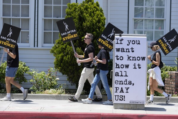 FILE - Picketers carry signs outside Amazon Studios in Culver City, Calif. on Monday, July 17, 2023. A tentative agreement between striking screenwriters and Hollywood studios offers some hope that the industry’s dual strikes may be over soon. (AP Photo/Chris Pizzello, File)