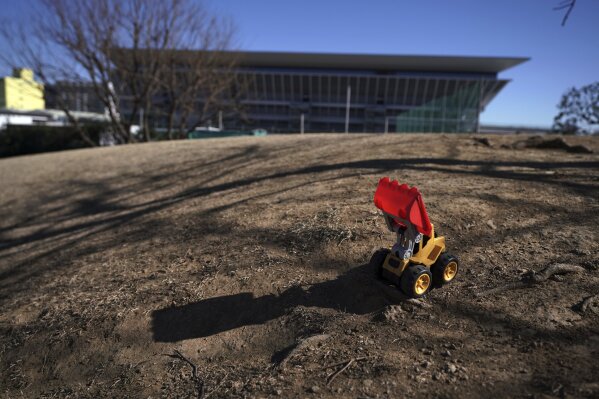 A leftover toy bulldoze is seen near the Tokyo Aquatics Center, one of the venues of Tokyo 2020 Olympic and Paralympic games, in Tokyo Wednesday, Jan. 20, 2021. The postponed Tokyo Olympics are to open in just six months. Local organizers and the International Olympic Committee say they will go ahead on July 23. But it’s still unclear how this will happen with virus cases surging in Tokyo and elsewhere around the globe. (AP Photo/Eugene Hoshiko)