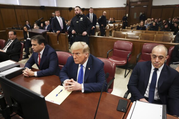 Former president Donald Trump, center, awaits the start of proceedings at Manhattan criminal court, Monday, April 22, 2024, in New York. Opening statements in Donald Trump's historic hush money trial are set to begin. Trump is accused of falsifying internal business records as part of an alleged scheme to bury stories he thought might hurt his presidential campaign in 2016. (AP Photo/Yuki Iwamura, Pool)