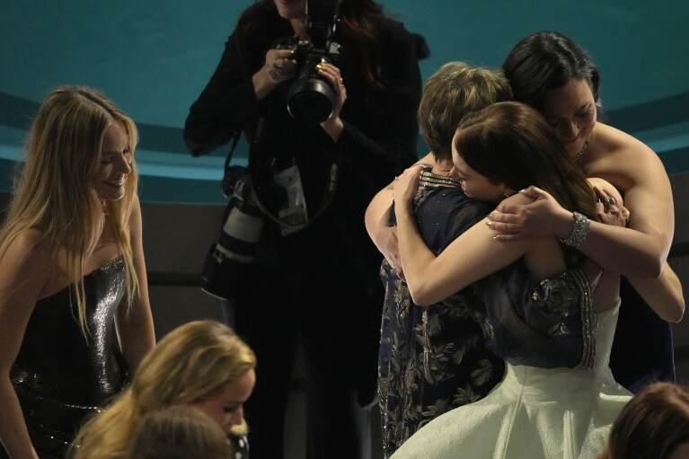 Margot Robbie, à l'extrême gauche, regarde Annette Bening, Lily Gladstone et Emma Stone s'embrasser lors de la cérémonie des Oscars, le dimanche 10 mars 2024, au Dolby Theatre de Los Angeles.  (Photo AP/Chris Pizzello)