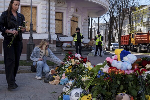 Women put flowers on a site of a Russian missile strike in Sumy, Ukraine, April 15, 2025. (AP Photo/Evgeniy Maloletka)